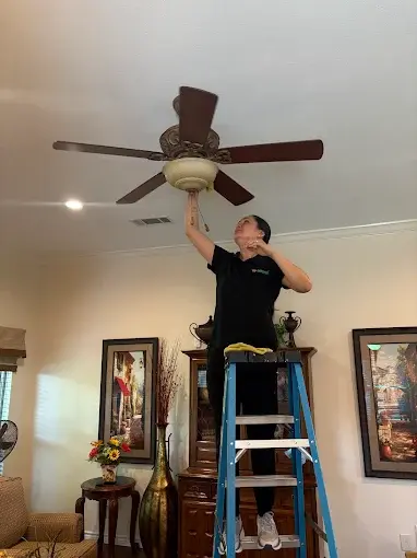 Ali Maid cleaner performing detailed ceiling fan cleaning during a deep cleaning service in Dallas, TX.
